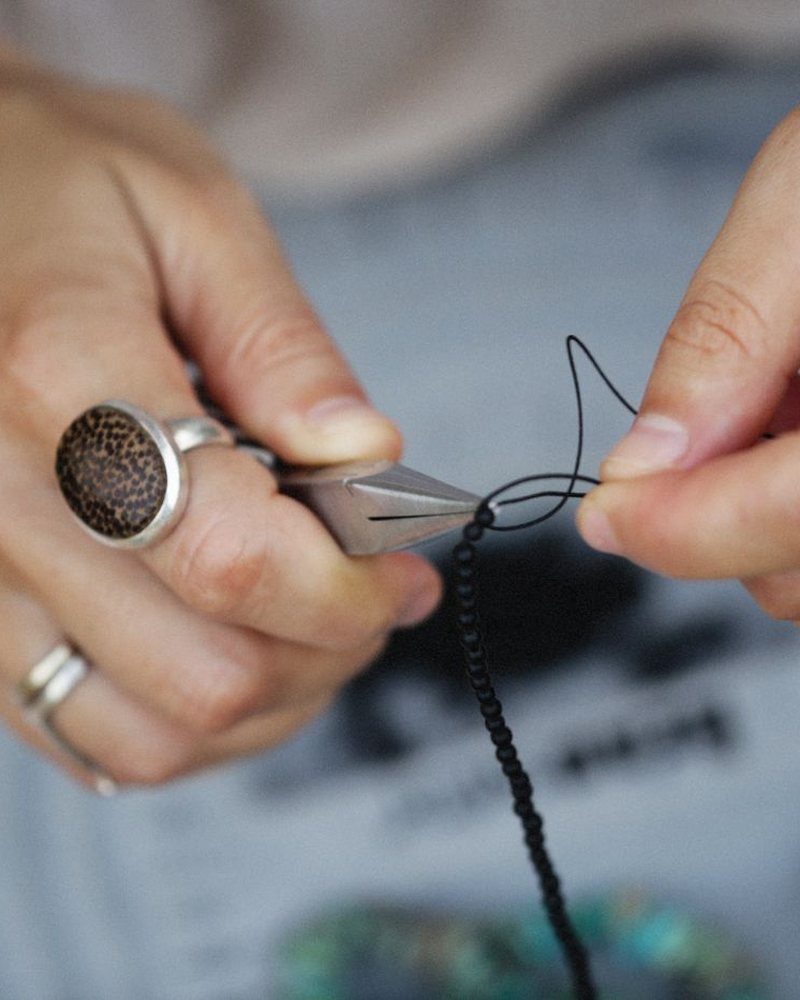 Older hands with silver rings tying a knot in a cord