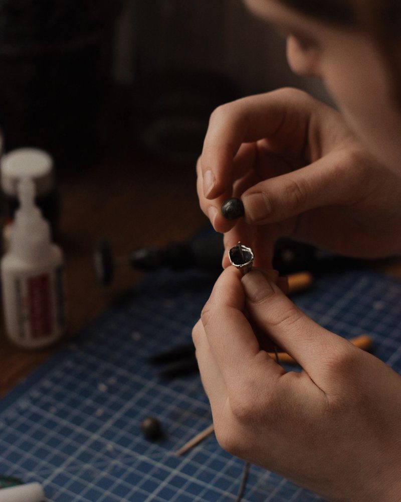 Hands finishing a small silver piece with a fine tool