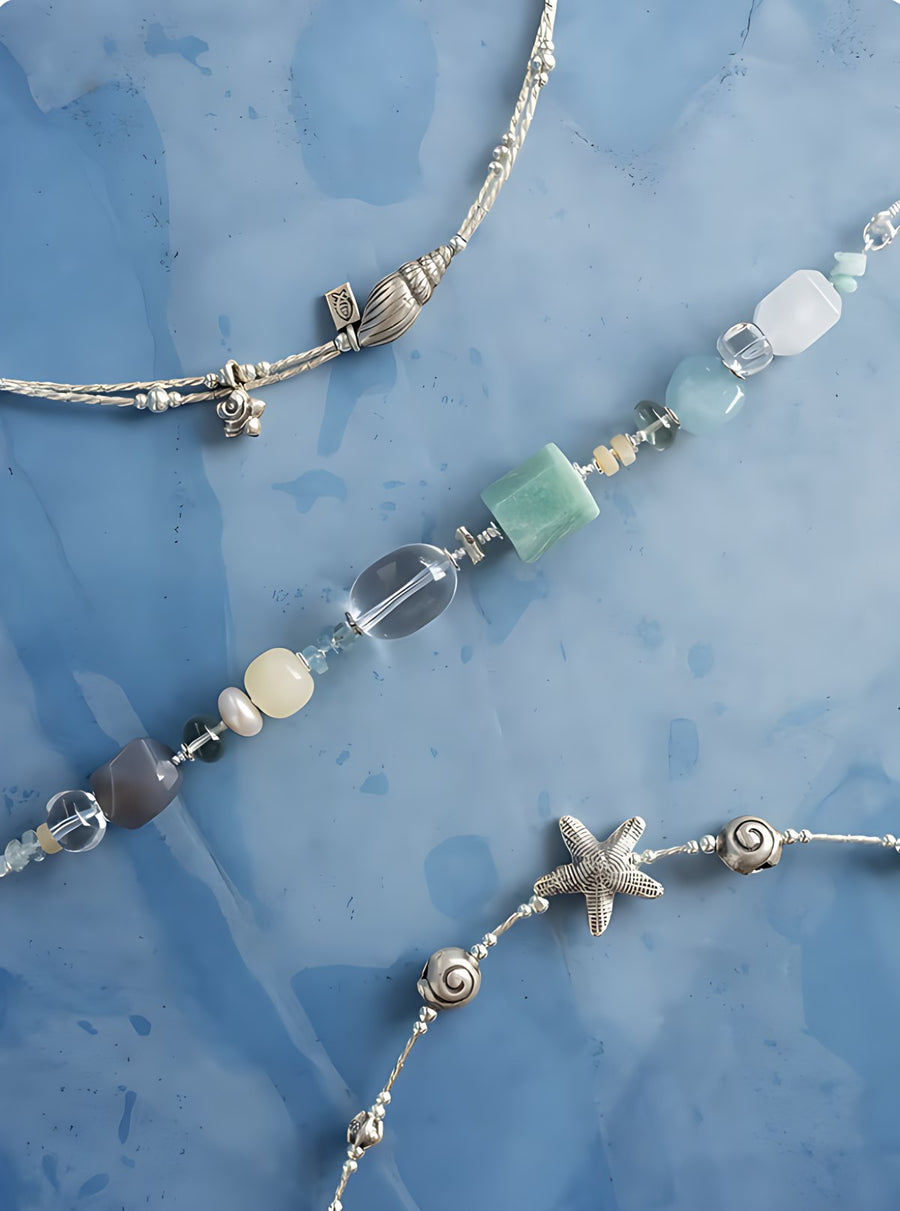 Silver chains with a starfish, shells and green stones on blue